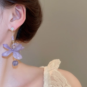 Close-up of a purple resin flower drop earring featuring zircon accents and gold plating