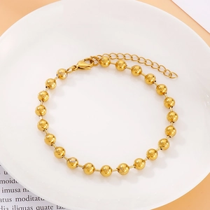 Detalle de una pulsera de cuentas huecas doradas con cierre de mosquetón y cadena ajustable