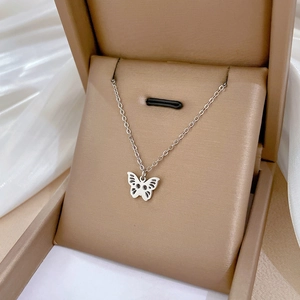 Detail of silver hollow butterfly pendant necklace placed inside a beige jewelry gift box