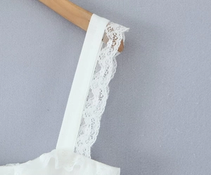 Close-up of white mini dress wide straps featuring delicate lace embroidery and frill edge