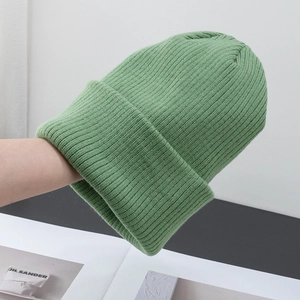 Dettaglio del berretto in maglia verde con trama a coste verticali e bordo ripiegato