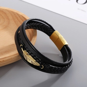 Close-up of black leather multi-layer bracelet with gold feather charm and magnetic clasp