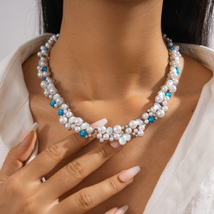 Close-up of layered necklace with blue and white faux pearls on model's neck