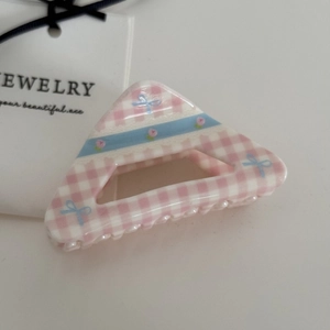 Detailed view of pink gingham hair claw clip with blue bows and floral patterns