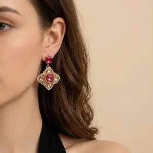 Vintage gold earrings with red ruby gemstone and pearl accents on model close-up