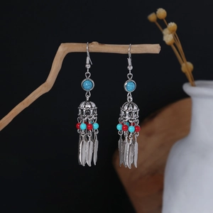 Bohemian tassel earrings with turquoise beads and silver feathers on a wood branch