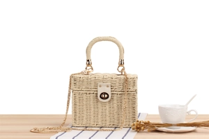 Detailed view of cream woven box bag with golden chain strap on a rustic wooden table