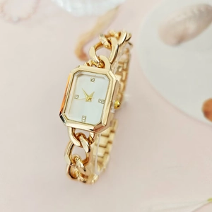 Macro detail of a square gold watch with a white dial and four diamond markers