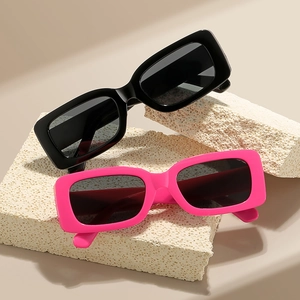 Retro square sunglasses in black and vibrant pink colors on a textured stone display