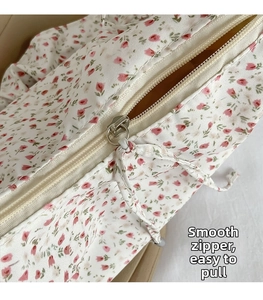 Detail of smooth metal zipper and floral fabric drawstring on the ivory crossbody bag