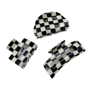 Three classic black and white checkered hair claws in geometric shapes on white background