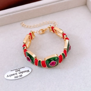 Dettaglio di un bracciale vintage dorato con smalto verde e pietre rosa preziose