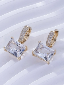 Close-up of emerald-cut zircon earrings with gold plating and pavé-set accents