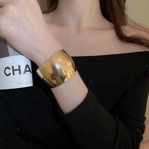 Polished gold knot open bangle bracelet shown on model with sleek metallic mirror finish