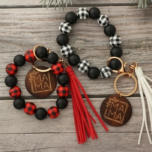 Macro detail of Mama wooden pendant and beaded wristlet with leather tassels