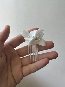 Detail of white ceramic flower and freshwater pearl on a bridal hair comb accessory