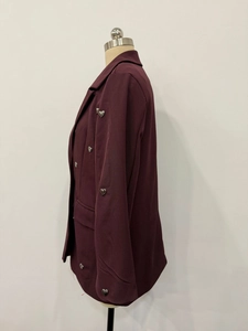 Detail of silver heart-shaped buttons on the sleeve of a burgundy blazer jacket
