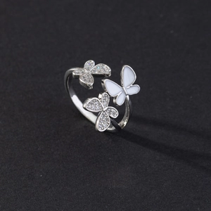 Detailed macro shot of an open silver butterfly ring with cubic zirconia and white enamel