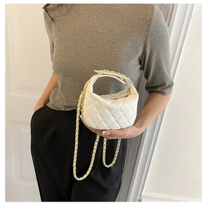 Close-up of white quilted mini chain bag with elegant gold hardware and handle detail