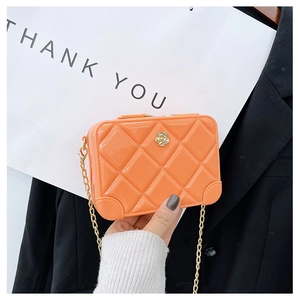Detail of orange jelly crossbody bag with quilted pattern, flower decor and gold chain
