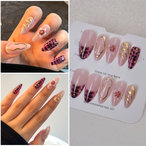Detailed view of almond-shaped y2k press-on nails with pink base and 3D gold embossed lines