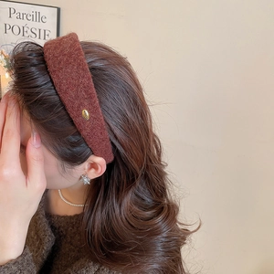 Gros plan du serre-tête en polaire marron avec badge doré pour un effet volumineux