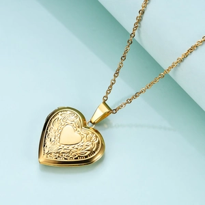 Detail of vintage gold heart locket necklace with floral vine engraving on blue backdrop