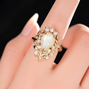 Vintage rose gold ring with pear-shaped opal and leaf engraving on black background