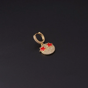 Close-up of gold-plated hoop earring with pavé zircon and red star motif on black backdrop