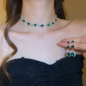 Detail of vintage silver necklace and earring set with green teardrop gemstones on model