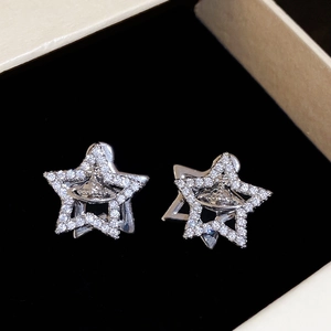 Macro detail of silver Saturn planet earrings with sparkling cubic zirconia on a black base