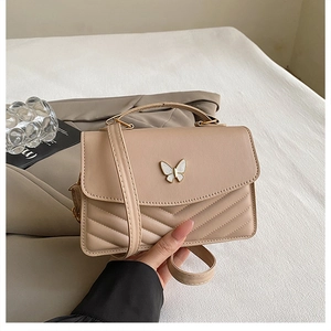 Detail of apricot crossbody bag with V-shaped quilting and butterfly metal buckle