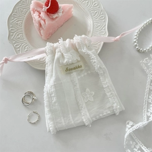 Detailed texture of white lace storage bag with pink drawstring and flower embroidery