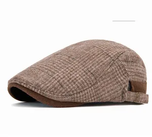 Detail of khaki plaid newsboy cap showing tweed texture and metal adjustment buckle