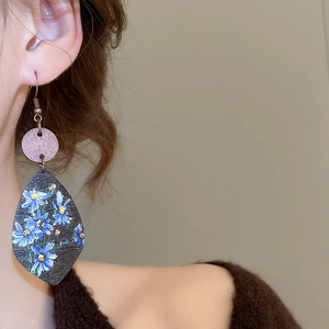 Detail of bohemian wood drop earrings with blue floral print on a model