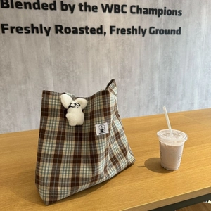 Detail view of retro plaid canvas coin purse with a cute white plush bunny charm attachment