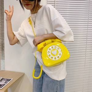 Close-up of a yellow patent leather crossbody bag in a retro rotary telephone design