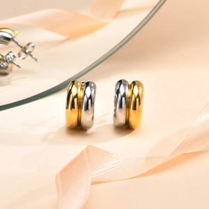 Detailed macro view of two-tone C-shaped metal earrings with gold and silver finish