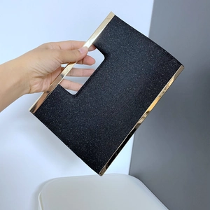 Detail of a black glitter clutch bag featuring a gold metal frame and elegant finish