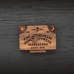 Macro view of wooden spirit board with engraved sun, moon symbols and alphabet detail
