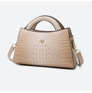 Close-up of beige crocodile pattern handbag with elegant gold V-shaped metal hardware