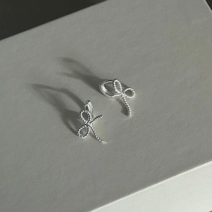 Macro shot of silver bow earrings with rope texture detail and secure clasp closure