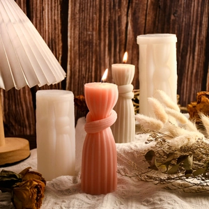 Artistic knot column candles in pink and white with vertical stripes on a wooden table