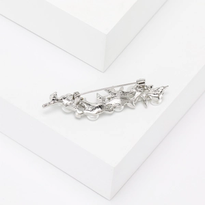 Detail view of silver plum blossom branch brooch with white pearls on a white prop