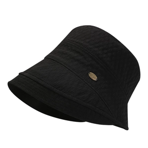 Detail of black bucket hat featuring thick honeycomb texture and bronze metal plate