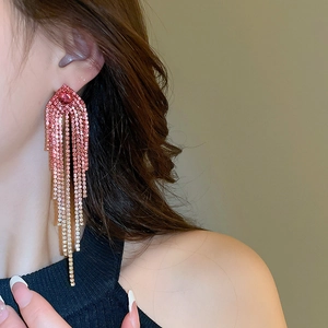 Close-up of long tassel earrings featuring gradient pink rhinestones on a female model