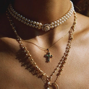 Layered gold necklaces with cross pendant and pearl choker set for a vintage aesthetic