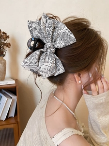 Detail of elegant oversized bow hair claw clip with black paisley print on white fabric