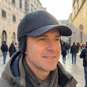 Winter men's wool blend baseball cap with ear flaps in dark grey worn outdoors