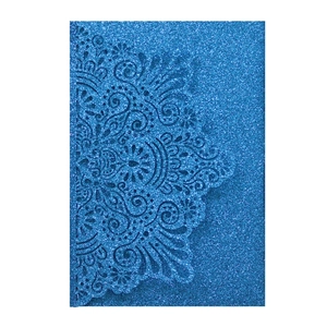 Macro shot of laser-cut mandala pattern on elegant blue glitter paper wedding invitation
